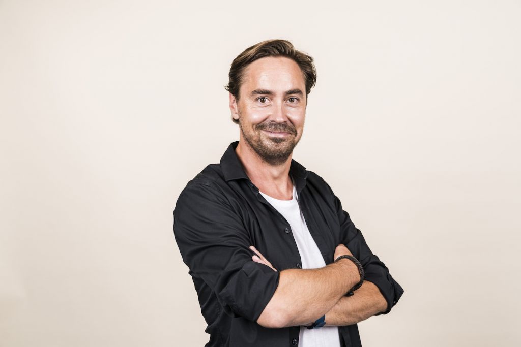 Zijn boek is de oogst van ‘tien jaar ondernemen’, aldus Marnix Geus. De ondernemer deelt in MensenHandel zijn weg als oprichter van Het PR Bureau in Amsterdam, de lessen die hij geleerd heeft als werkgever en vooral: zijn plezier en zijn ergernissen. Wat dat laatste betreft: Geus maakt van zijn hart geen moordkuil. Hij heeft bijvoorbeeld een broertje dood aan de term ‘baas’. Want een ‘baas’, zo stelt hij, heeft ‘personeel’, nog zo’n belemmerende term. Personeel impliceert een gedienstige houding, een misplaatste onderdanigheid. De lol van het werk verdwijnt stilletjes bij wie die term als vanzelfsprekend gebruikt. En bazen? Die mogen dan de leiding hebben, in de praktijk zijn ze ‘het afvoerputje van de onderneming’ – alle problemen komen bij hen terecht… Een recept voor een giftig werkklimaat. Dat kan beter, vindt Geus, die met Het PR Bureau vijf keer op rij de titel Great Place to Work verdiende. Een verborgen missie van Geus met zijn boek is dan ook om een nieuw taalgebruik te lanceren op de werkvloer. Want: ‘de werkgever moet bevrijd worden van al die traditionele denkbeelden over arbeidsrelaties die hem volledig in de weg zitten in deze tijd.’ Bij dat nieuwe taalgebruik hoort de titel van zijn boek: MensenHandel. Immers, mensen zijn handel – of liever: mooie mensen zijn goede handel. Maar wat kunnen werkgevers en werknemers hiervan leren? Geus verkocht begin vorig jaar zijn aandelen in Het PR Bureau en stortte zich op zijn nieuwe droom: The Present Movement. Naast deze community waarmee hij ondernemers koppelt aan de vluchtelingencrisis, is hij actief als groeicoach, spreker en grootaandeelhouder in pr-bureau Blyde voor duurzame merken. In dit artikel drie lessen voor werkgevers van Marnix Geus. 1. Waardeer je mensen en vier je successen Dat doe je door je mensen te waarderen en samen successen te vieren. ‘Allebei hebben ze te maken met wat goed gaat. Dat waarderen hebben we altijd enorm gedaan. Vieren trouwen ook.’ In Nederland is het vaak droevig gesteld met waardering en viering: wij zijn vaak direct in onze communicatie, altijd to-the-point. Maar zou het niet leuk zijn om elkaar even te leren kennen voor we ter zake komen?’ Neem dus de tijd om verbinding te maken, vindt Geus. Kijk naar de individuele talenten van je team. Maak er gebruik van om iemand de kans te geven dingen te doen die hij of zij leuk vindt. En kan diegene dat nog veel groter maken, misschien? Allemaal kansen, aldus Geus. Vieren, dat deed Geus in zijn onderneming onder meer in de wekelijkse stand-up-meetings. ‘We bespraken dan alle bijzonderheden die onze mensen meemaakten. Een nieuwe klant, een leuke kennismaking, een afgerond project, verjaardagen, een goede maand, relaties. Je moet geen kans voorbij laten gaan voor een borrel.’ Nog iets wat Geus deed: zijn KPI’s omdenken. ‘Hoeveel kurken hebben we dit jaar ontpopt? Kan dat aantal volgend kwartaal niet omhoog?’ 2. Wees altijd bereid om hulp te vragen Maar wat als er geen reden is voor een feestje? In 2015 ging het bergafwaarts met Het PR Bureau. De omzet liep terug en er moesten mensen weg uit het bedrijf. Een half jaar eerder ging het met Geus zelf ook niet goed. ‘Ik dacht dat ik mijn grenzen kende. Maar ik had privé een dreun opgelopen en werd steeds vaker ziek en was moe. Ik vertelde het mijn partners. Dat moest ik leren: om hulp te vragen. Mezelf kwetsbaar op te stellen.’ Hoe je dat doet – goed voor jezelf zorgen? Geus herkent de tekenen: ‘Als je te veel stress hebt, krijg je een tunnelvisie, ga je sneller praten, hoog ademen en vaak ook ongemerkt hyperventileren.’ Signalen, die ook direct merkbaar zijn in je agenda. ‘Je gaat bezuinigen op wat je leuk vindt, op afspraken met vrienden, op sport.’ Wees dat voor en neem de tijd om voor jezelf te zorgen. Want wie niet voor zichzelf kan zorgen, kan ook niet meer goed voor zijn mensen zorgen. 3. Zorg voor veiligheid én uitdaging ‘Goed werkgeverschap is net als een gezonde opvoeding: je zorgt enerzijds voor veiligheid en anderzijds voor uitdaging.’ Volgens Geus laten veel organisaties het op veiligheid afweten. ‘Sla de vacatureteksten er maar op na. Bedrijven zoeken proactieve, flexibele, innovatieve, dynamische, creatieve, out-of-the-box-denkers, die snel kunnen schakelen. Die teksten suggereren dat de medewerker een soort ondernemer is, die toevallig in loondienst werkt. Met uitdagen is niets mis, maar als je mensen zich niet veilig voelen, dan gaan ze dingen doen die ze zelf niet willen, en daar gaat het al gauw mis in de relatie tussen werkgever en werknemer. Want niemand wil een soort hond in zijn bedrijf, die altijd maar in je nek blijft hijgen.’ En ook aan het bieden van uitdaging schort het bij veel werkgevers. Geus vindt dat er te weinig open vragen worden gesteld door leidinggevenden. ‘Simpele vragen als: waar zou jij komend jaar heel graag aan willen bijdragen? Of: wat zou je heel graag ooit in je leven willen doen? Wat is een grote droom van jou? Als je dat van elkaar weet – en wij hebben zulke sessies met mensen in het team gehad – dan kun je mensen stimuleren om hun droom serieus te nemen.’ Geus hielp ze door te bedenken welke stap ze als eerste moeten zetten om hun toekomstdroom te realiseren. Dat kan ertoe leiden dat mensen hun baan opzeggen. Niet erg, vindt Geus. ‘Het moet leuk zijn om bij ons te werken, maar ook op een dag leuk zijn om bij ons weg te gaan. Wat is er mooier dan dat mensen na vijf jaar zeggen dat ze écht verder zijn gekomen in hun leven?’